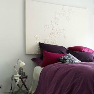 dormitorio blanco con textiles morados y cabecero blanco