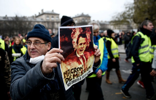 640x410_a-demonstrator-holds-a-placard-displaying-a-picture-a-french-president-emmanuel-macron-with-the