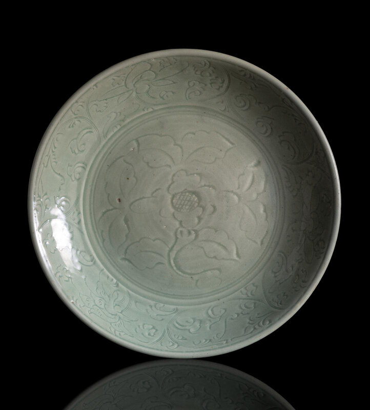 A large celadon-glazed Longquan charger with a large incised peony blossom in the center and lotus scrolls, early Ming dynasty