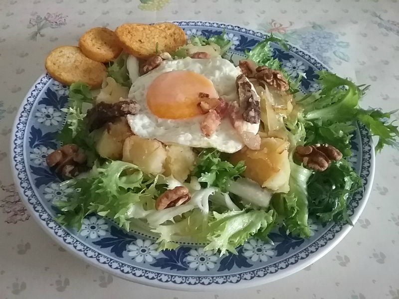 Salade frisée aux lardons aux œufs sur le plat avec des croutons
